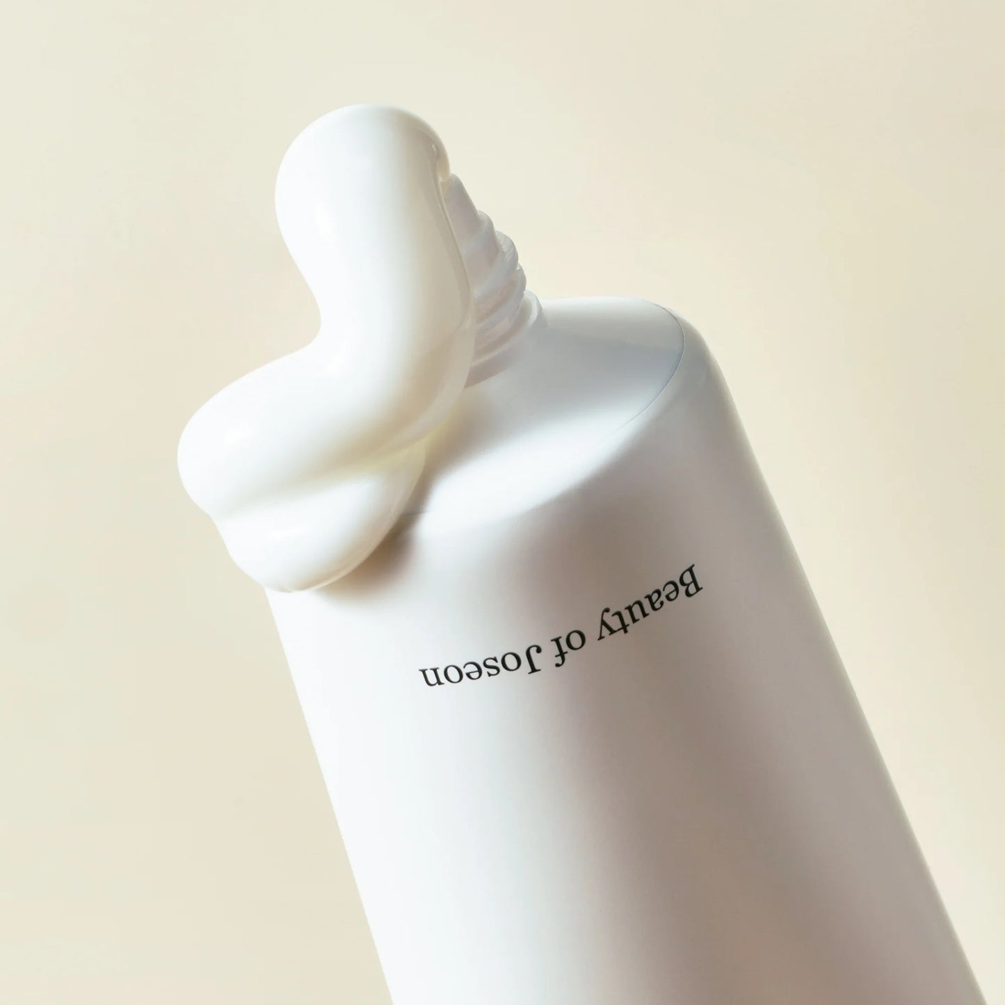 White bottle with a decorative cap on a beige background, featuring the brand 'Beauty of Joseon'.