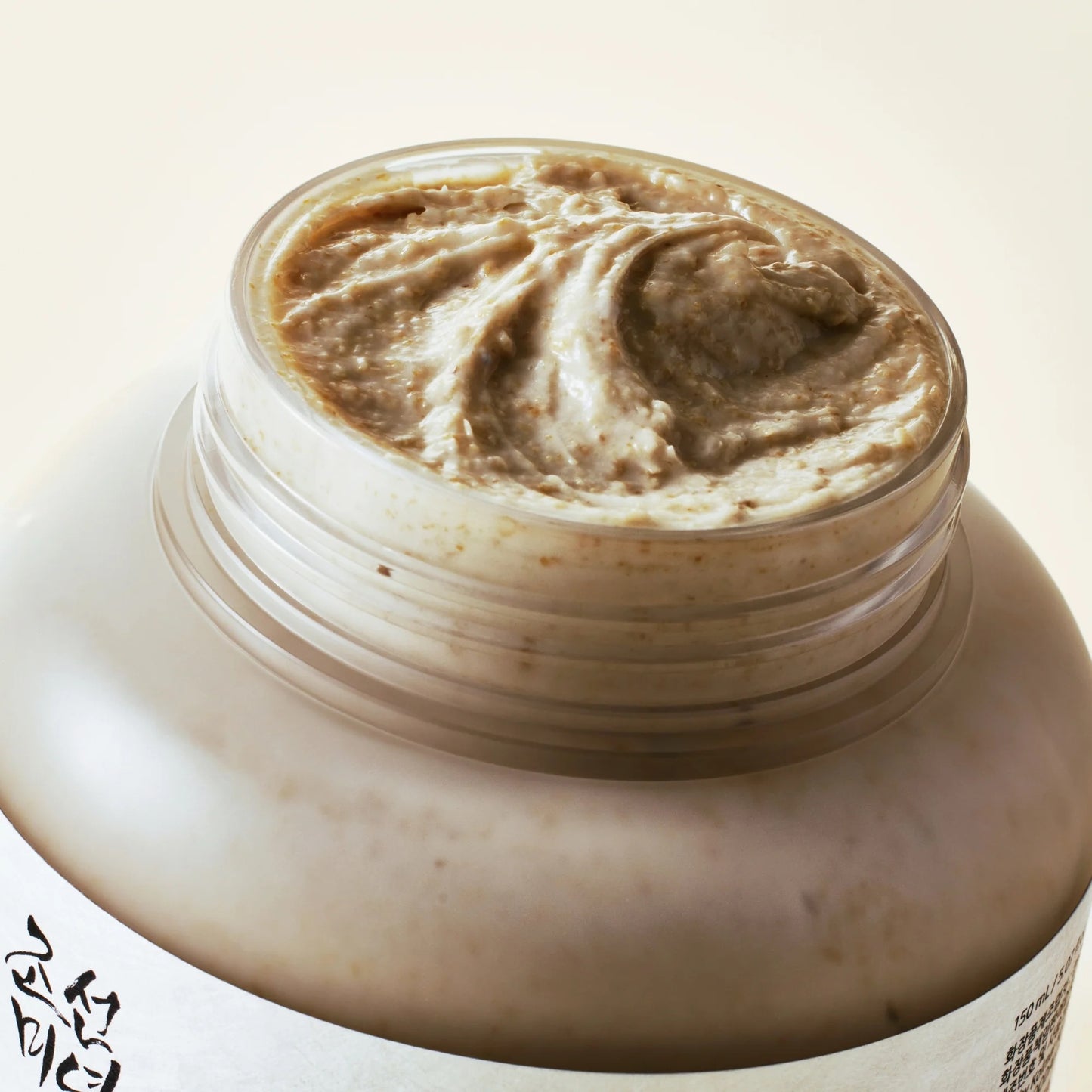Jar of brown cream with a swirled top on a beige background