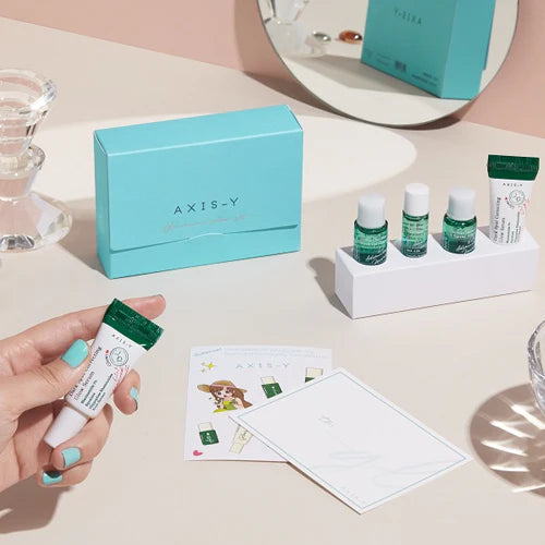 Axis-Y skincare product set on a table with a hand holding a tube.