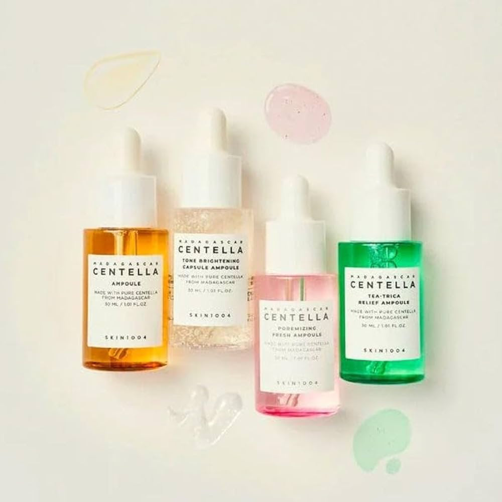 Four skincare bottles with different colored liquids on a light background