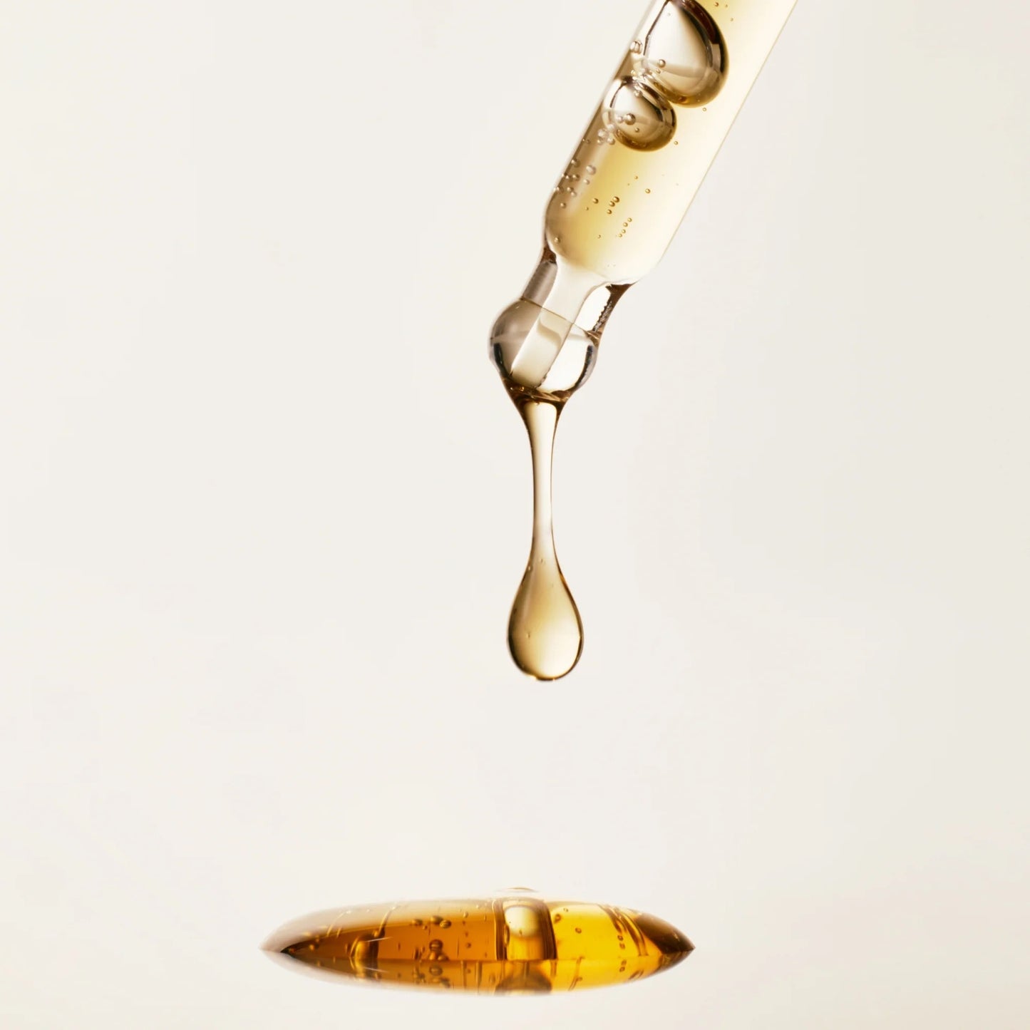 Close-up of a dropper with liquid being dispensed on a light background