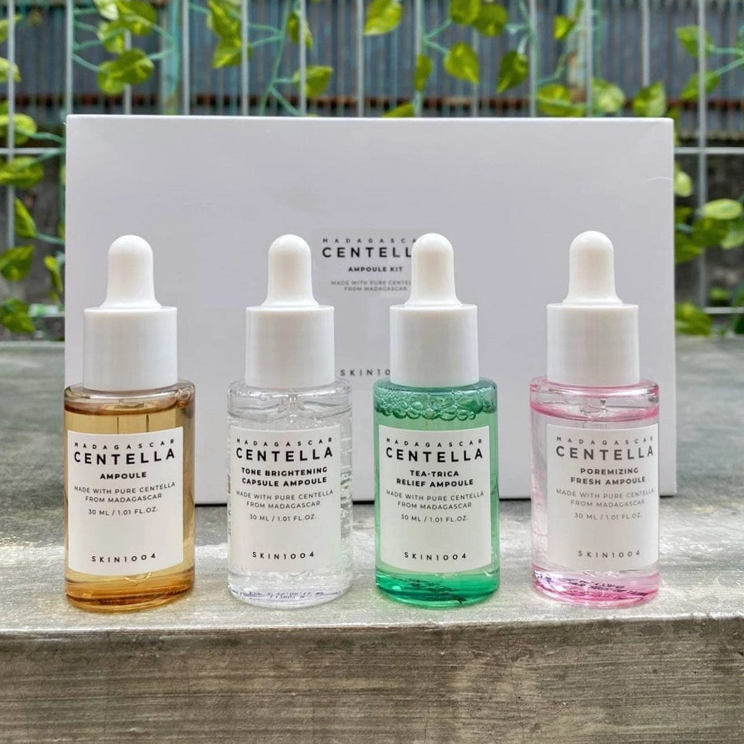 Four Skinceed Centella Ampoule bottles on a wooden surface with a white box in the background.